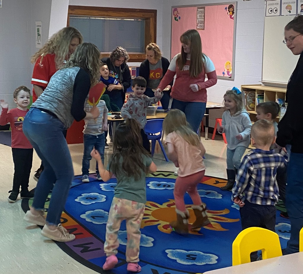 Children and teachers dancing on a colorful carpet