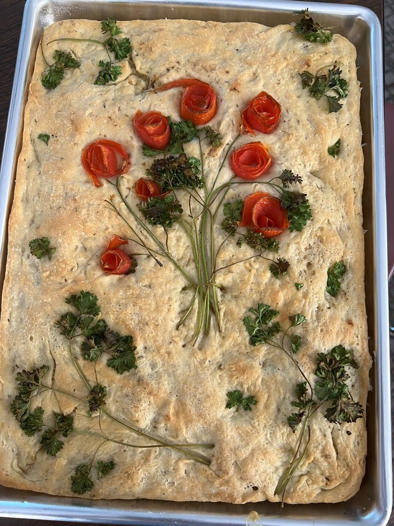 A gardenscape focaccia bread with a bouquet of roses in the middle.