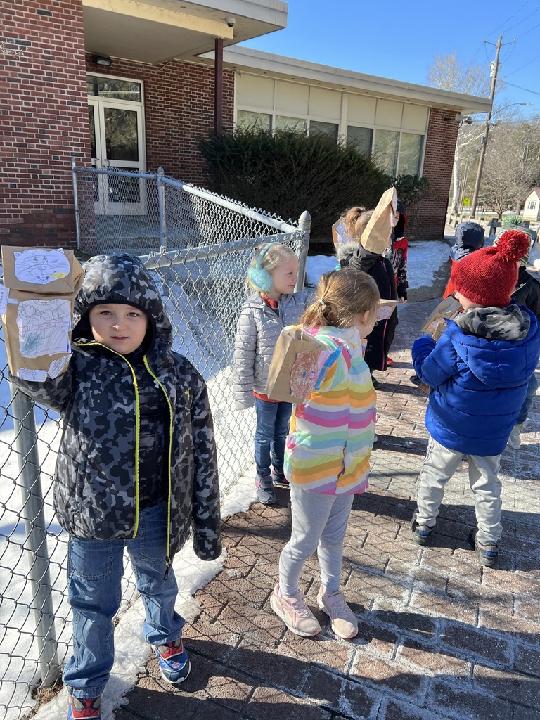 Students hold up groundhog puppets made with paper bags