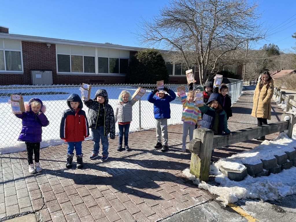 students line up along a fence with groundhog puppets