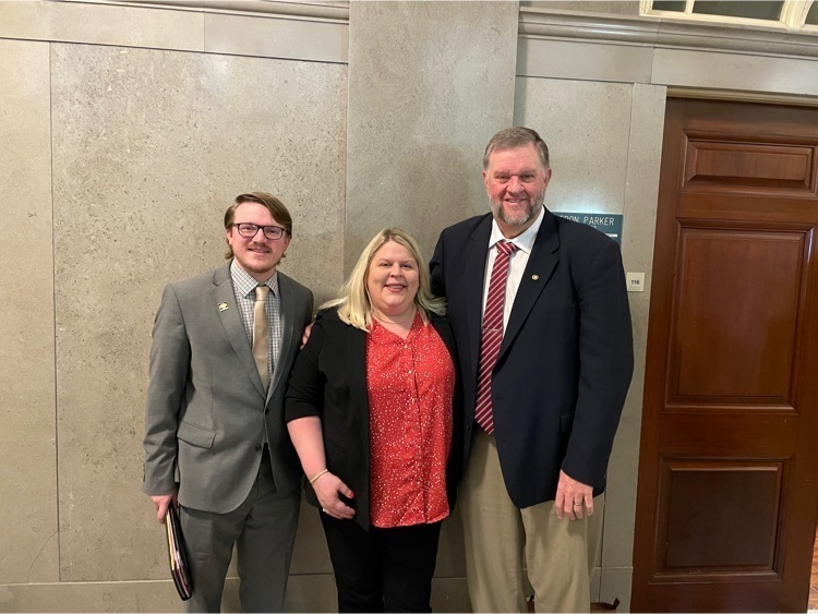 two men and a woman standing against a wall