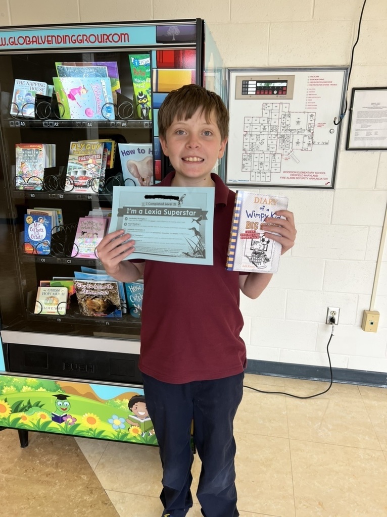 student holding certificate and book in front of book machine