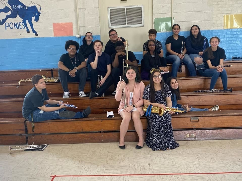 Members of the band smiling on bleachers