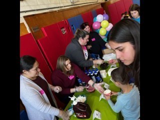 5 adults and 1 student standing at a table with green table cloth selecting ice cream and toppings