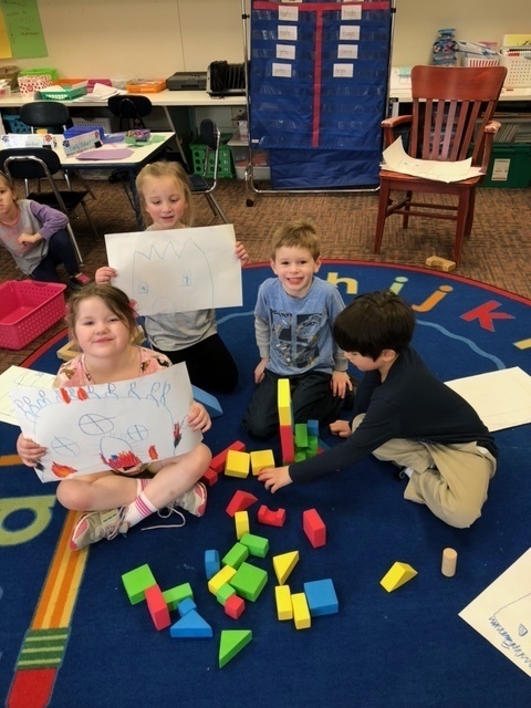 Group of children holding their designs and building with blocks