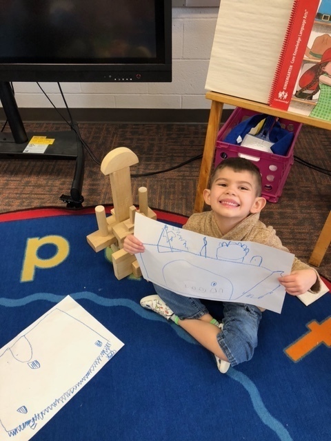Child holding their design beside building blocks