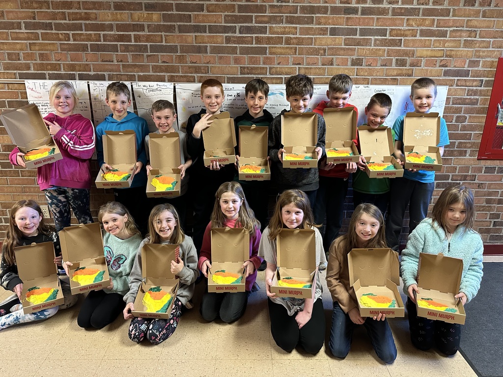 STudents stand in rows holding their Wisconsin landform region models made out of salt dough