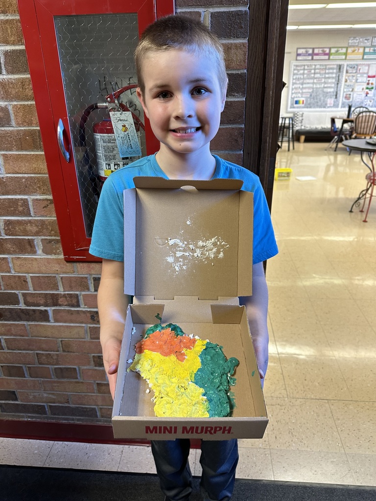 a student holds his Wisconsin landform region models made out of salt dough