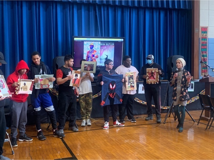 students stand in front of the school holding art they made