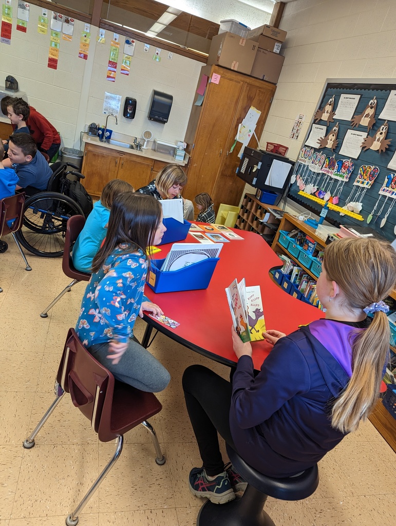 4th grade students sit with 1st grade students in their classrooms at tables and read