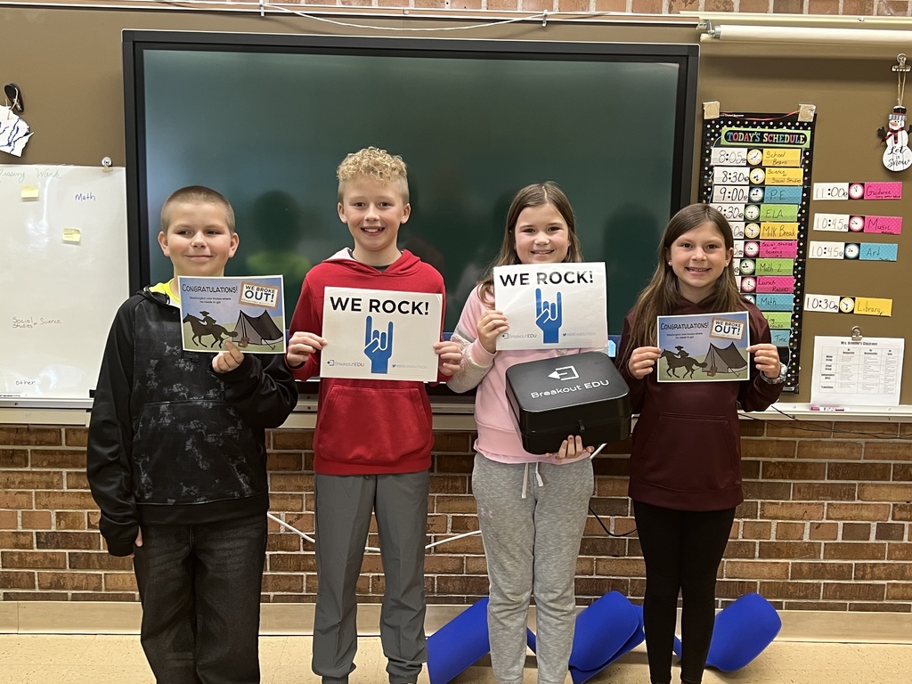 students hold up signs to show they solved all the clues and broke out