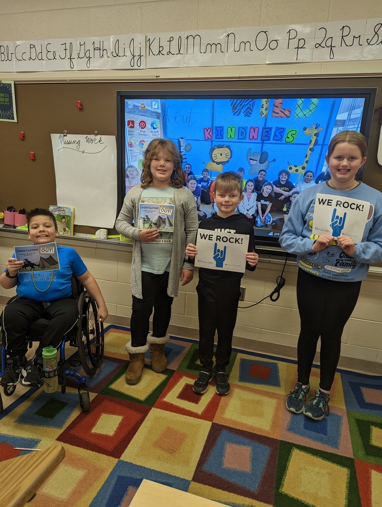 students hold up signs to show they solved all the clues and broke out
