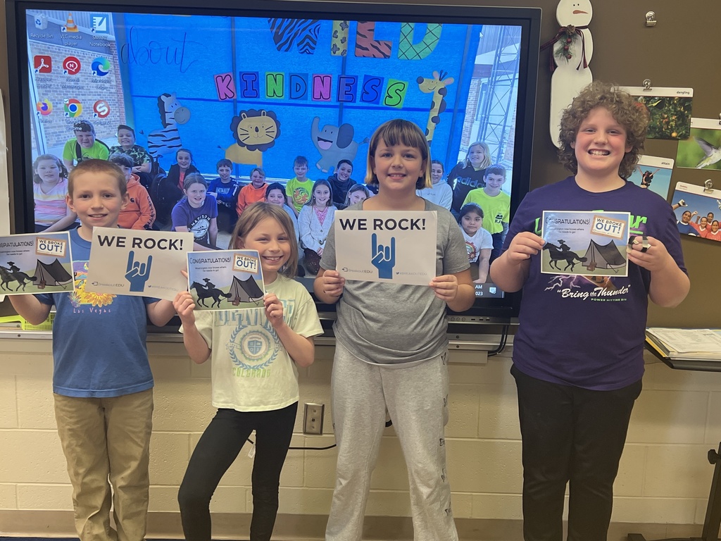 students hold up signs to show they solved all the clues and broke out