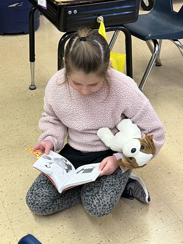 a student reads a book with her stuffed animal