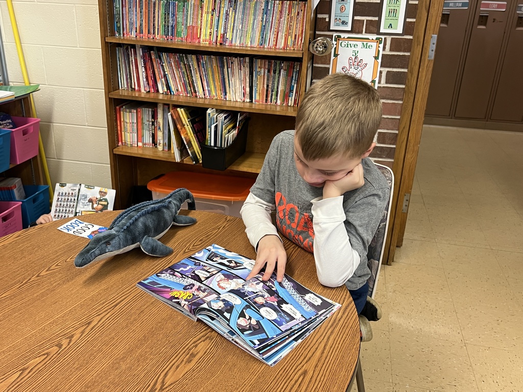 a student reads a book with her stuffed animal
