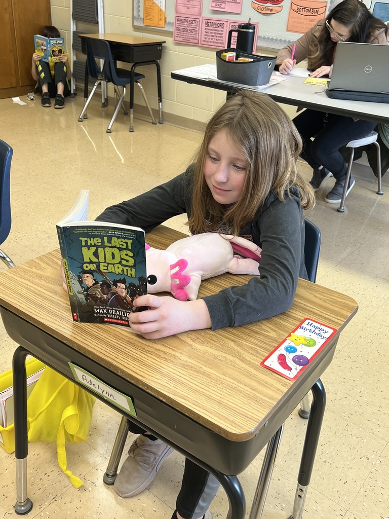 a student reads a book with her stuffed animal