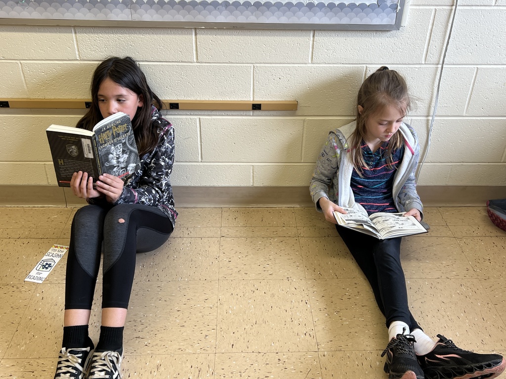 2 students read their book with their stuffed animals