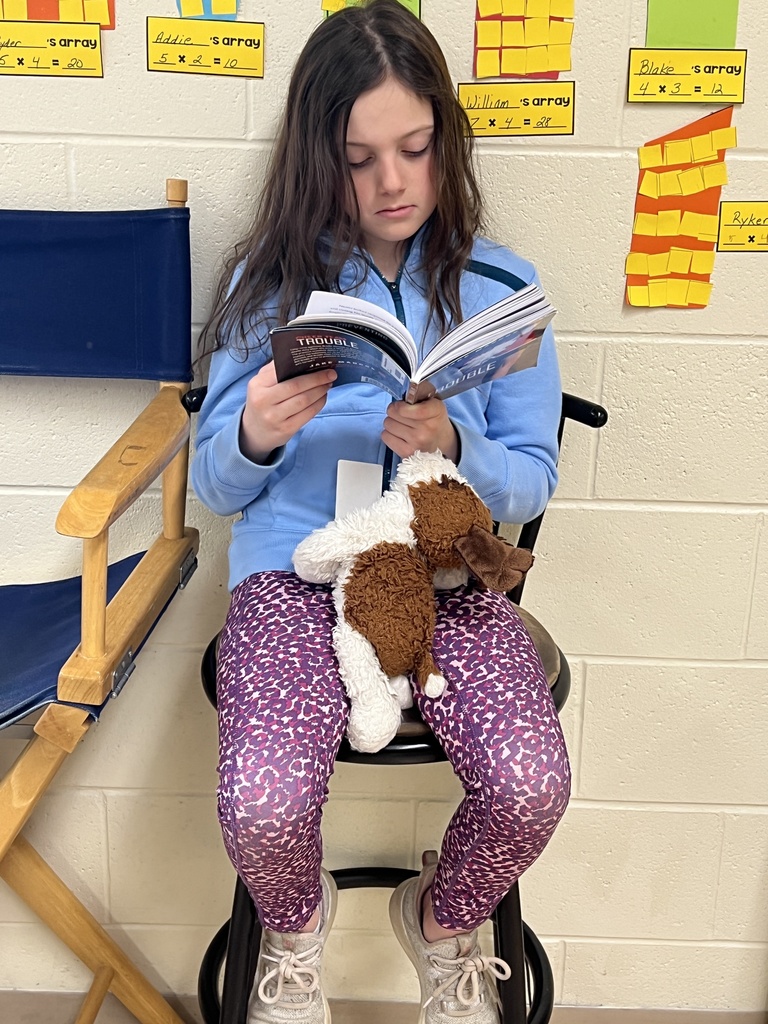 a student reads a book with her stuffed animal
