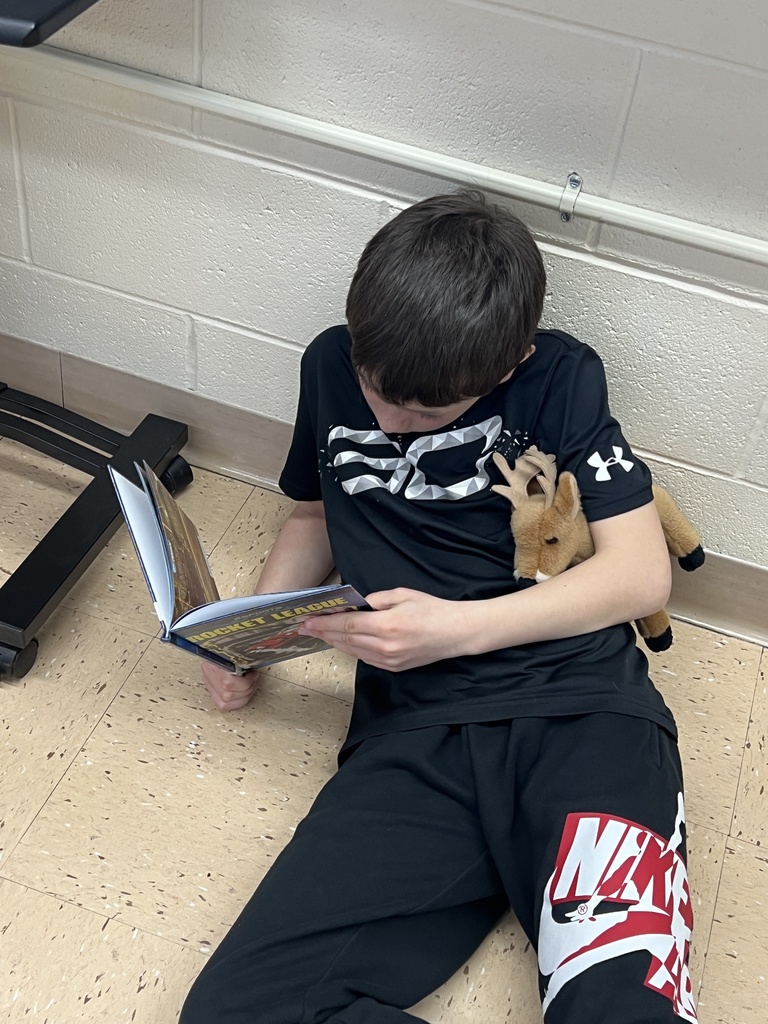 a student reads a book with her stuffed animal