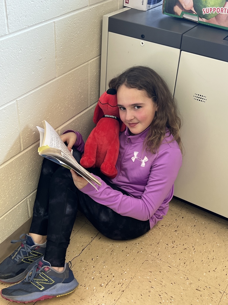 a student reads a book with her stuffed animal