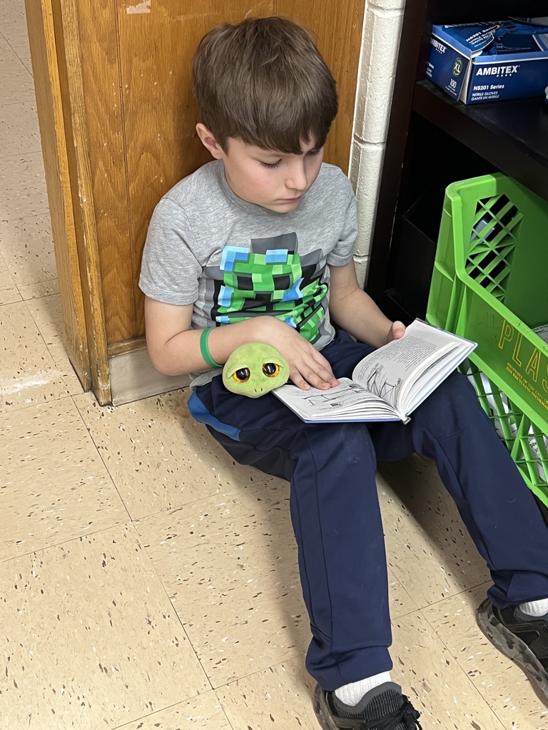 a student reads a book with her stuffed animal