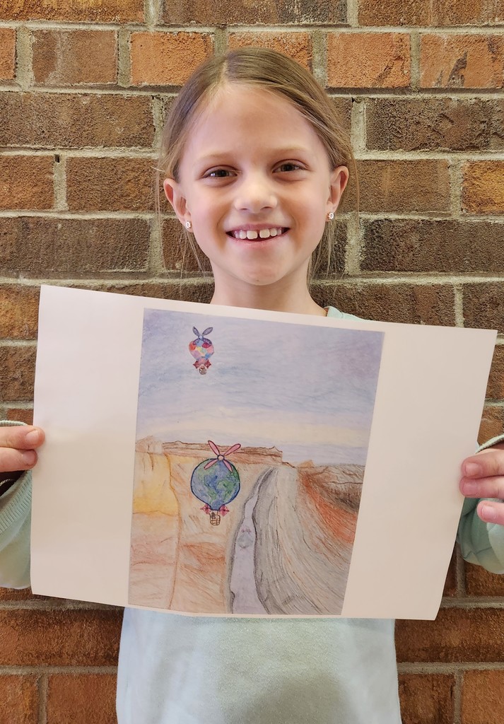 a student holds up her winning entry for an aviation art contest in wisconsin