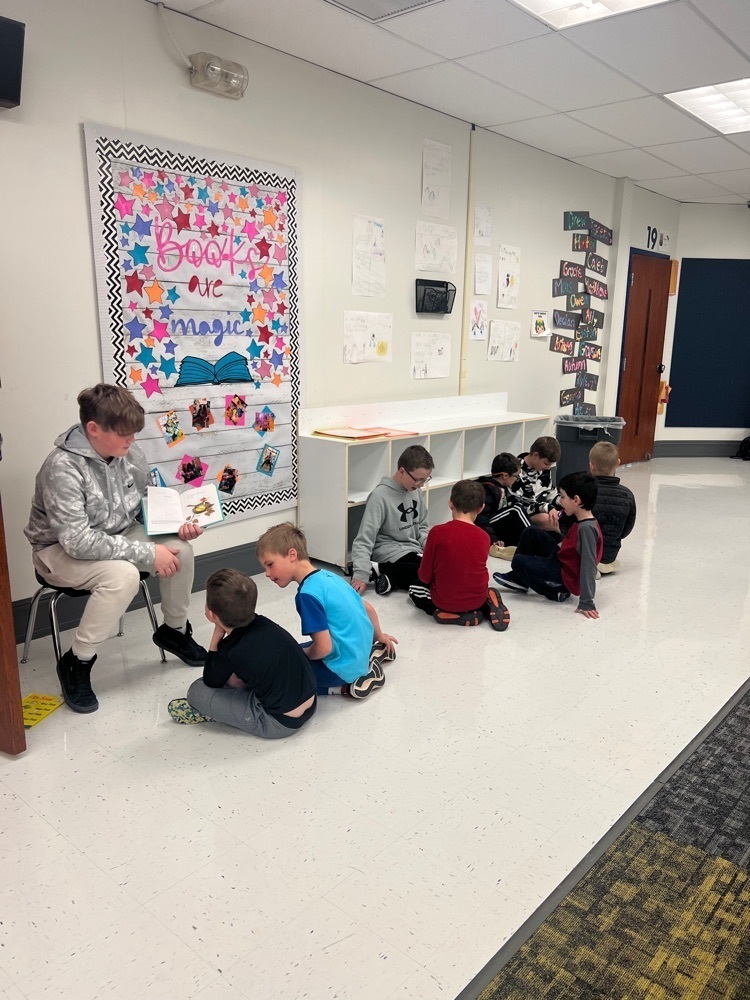 A middle school boy reading to young students 