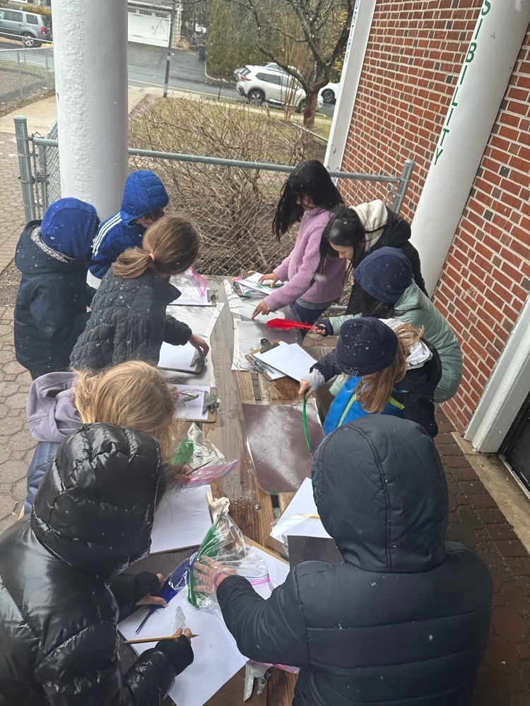 a group of 5th grade students gathered around a table observing snowflakes