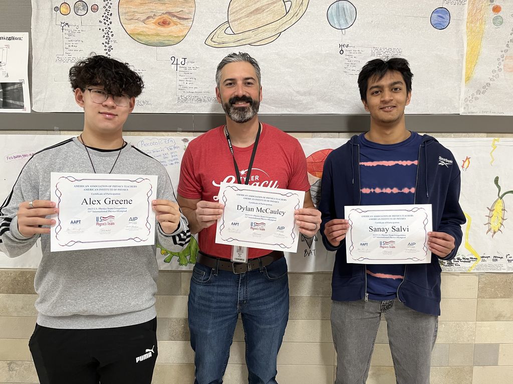 Legacy students Alex Greene and Sanay Salvi with Mr. Ray (holding Dylan McCauley's certificate) pose with their certificates for participating in the US Physics Olympiad