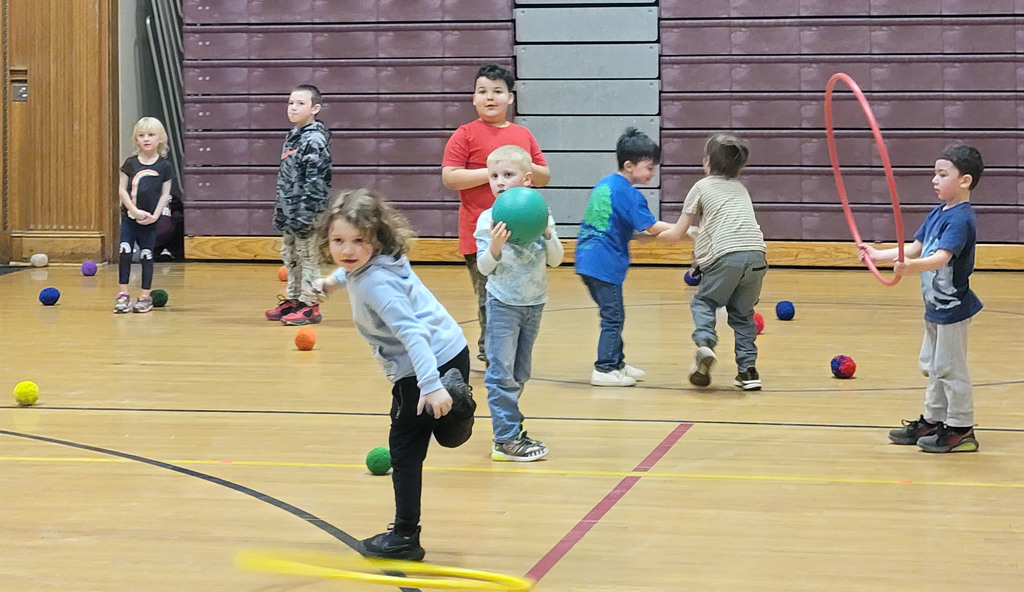 Students play with hula hoops and balls in the gym