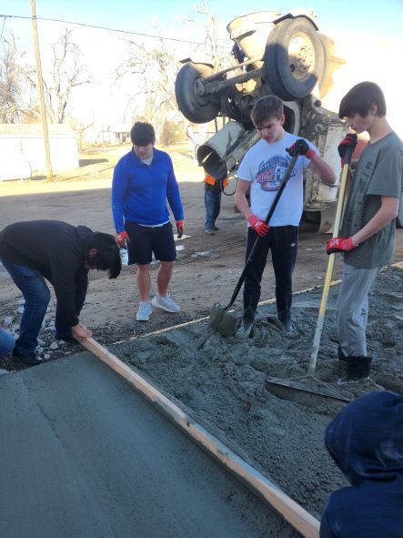 Students pouring a cement pad. 