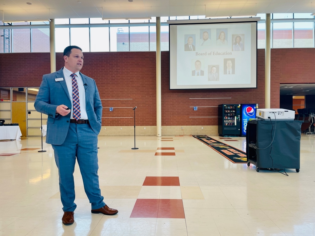 man speaking in a large room in a school