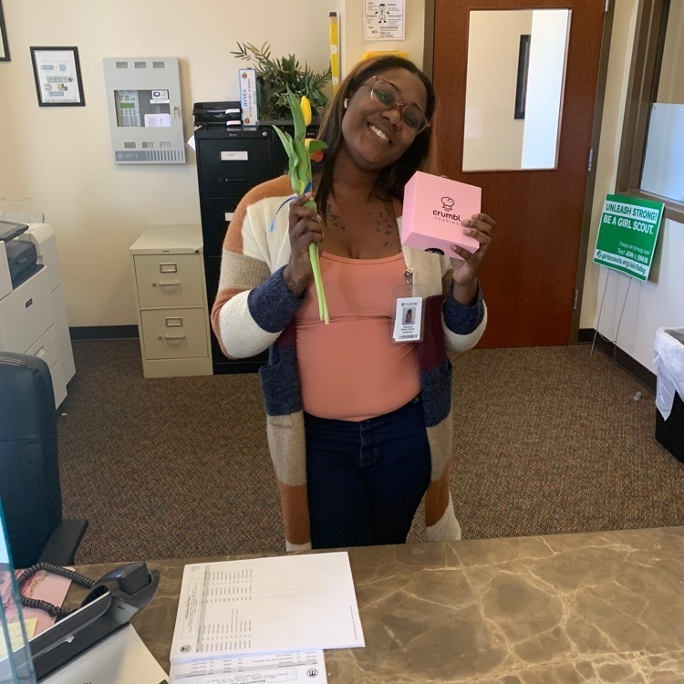 front office staff holding flowers and a cookie
