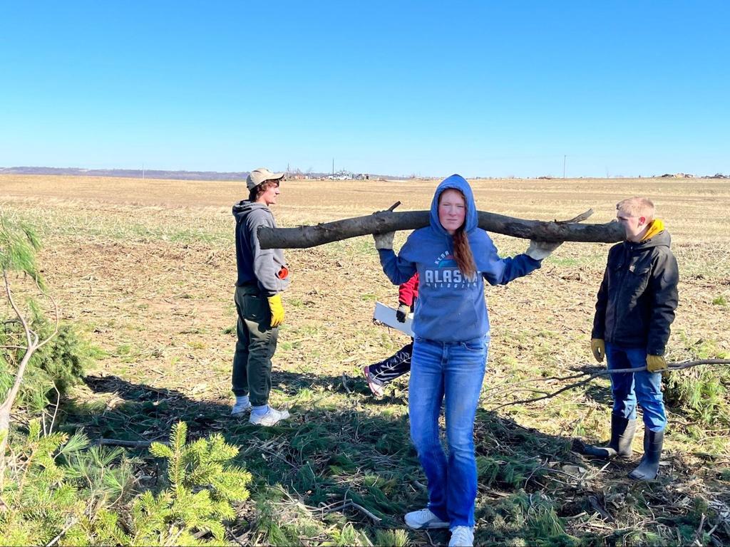 Students working to clean up tornado damage debris