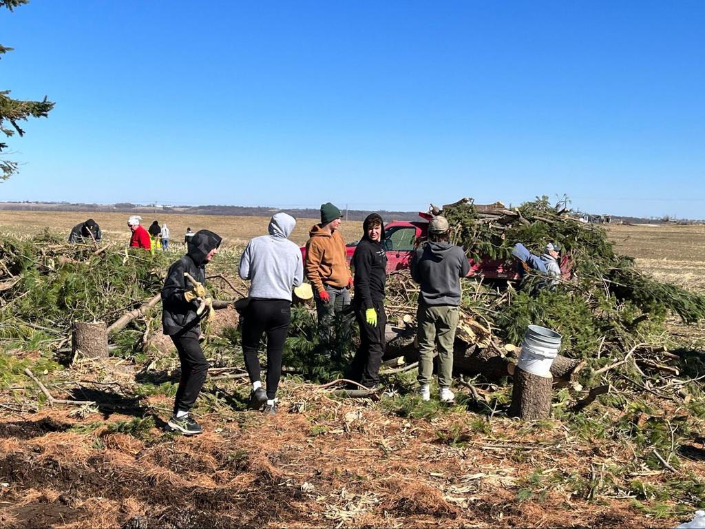 Students working to clean up tornado damage debris