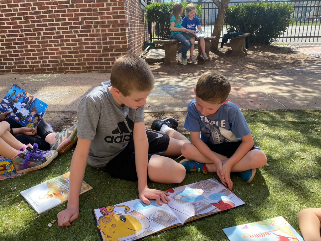 Two boys reading outside together