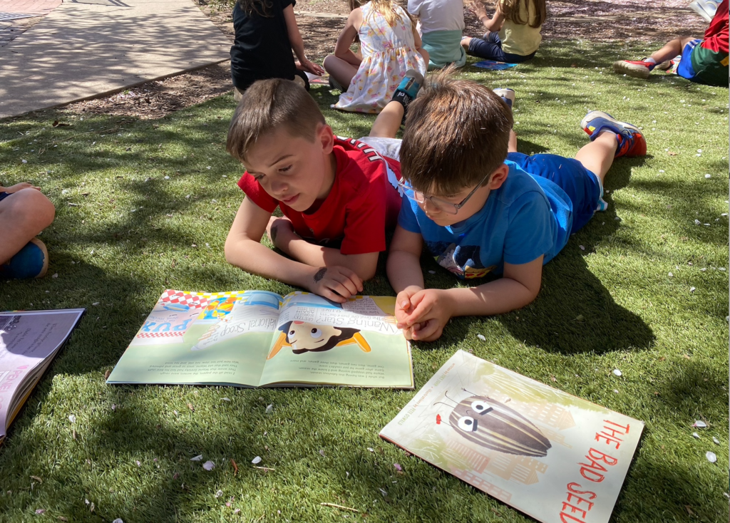 Two boys reading outside together