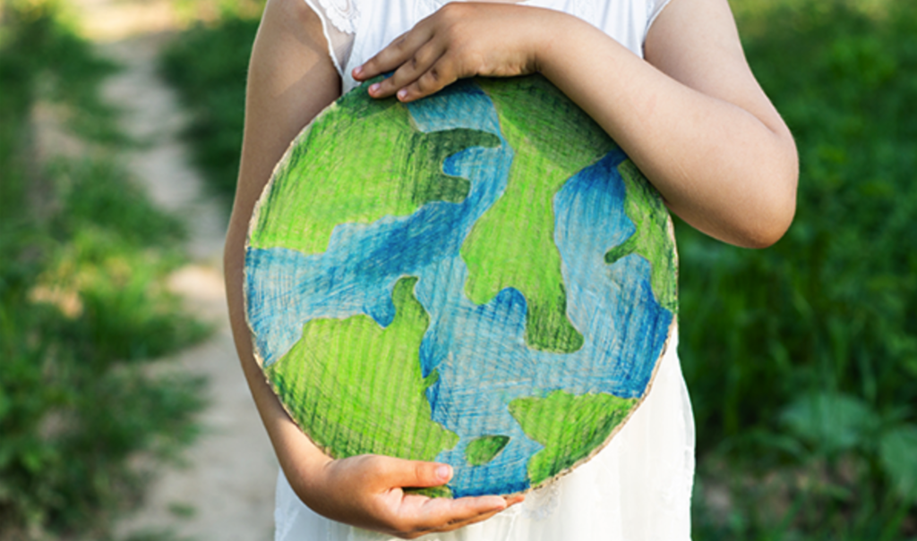 child's arms and hands cradling a cardboard circle that is colored to represent earth.