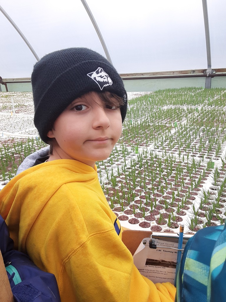 A student looks back over his shoulder with plants to the front of him