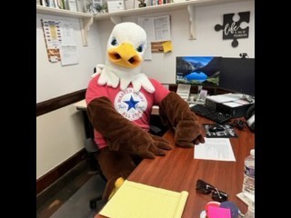 large eagle mascot sits at the principles desk