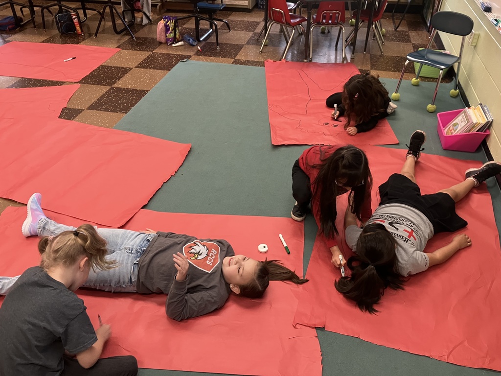 RCCS students laying on red paper taking measuremnts