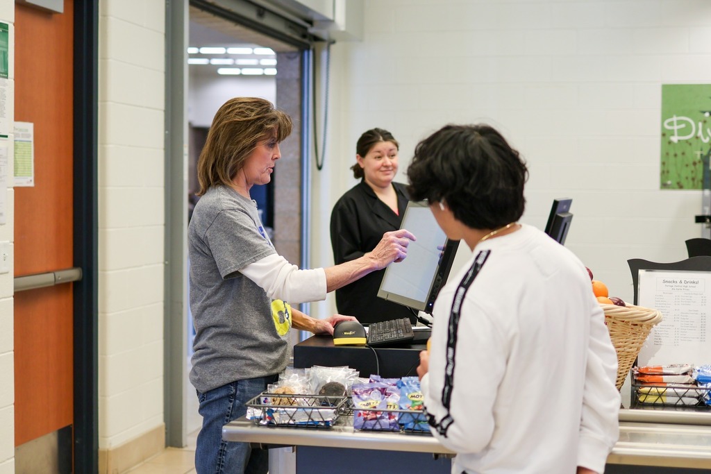 Food service workers check out a student