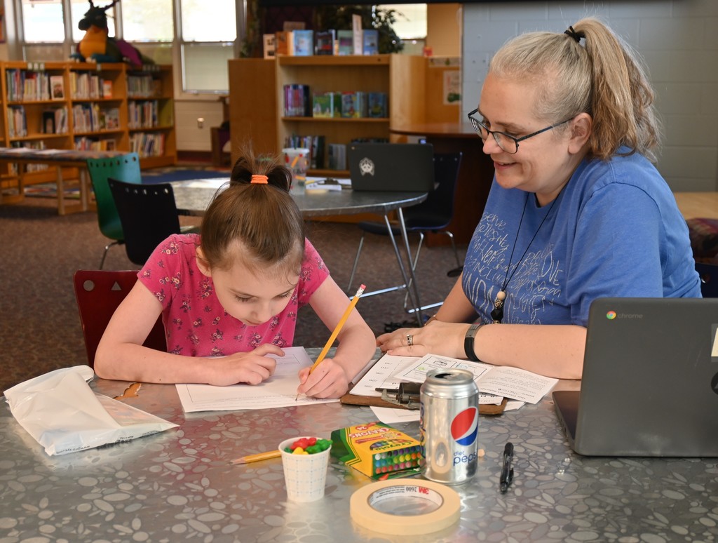 student & teacher seated in library