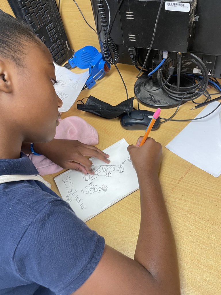 A student focuses on a dinosaur drawing.