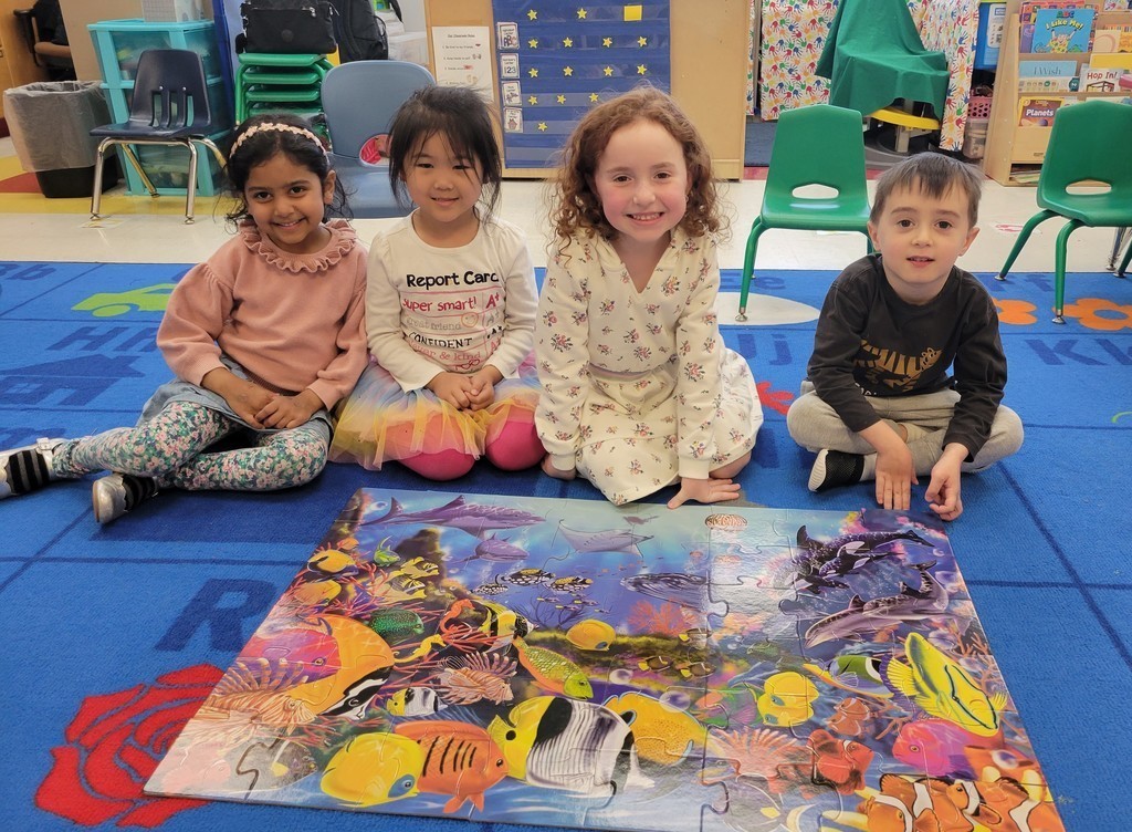 Kindergartners pose for picture in front of floor puzzle