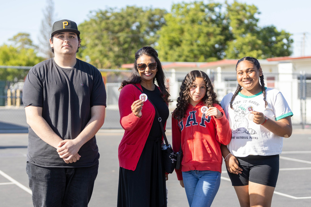 Principal Arti Narayan with logo designer Pedro Diaz and Carroll Fowler students holding logo stickers