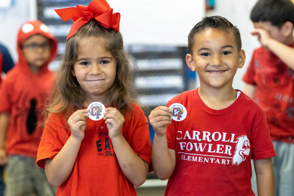 Young male and female students holding logo stickers