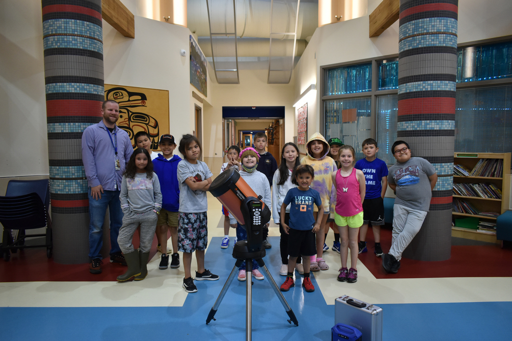 students standing in school with a large telescope