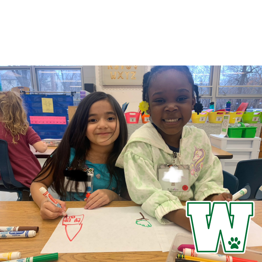 Two Kindergarten students smiling for a photo while coloring