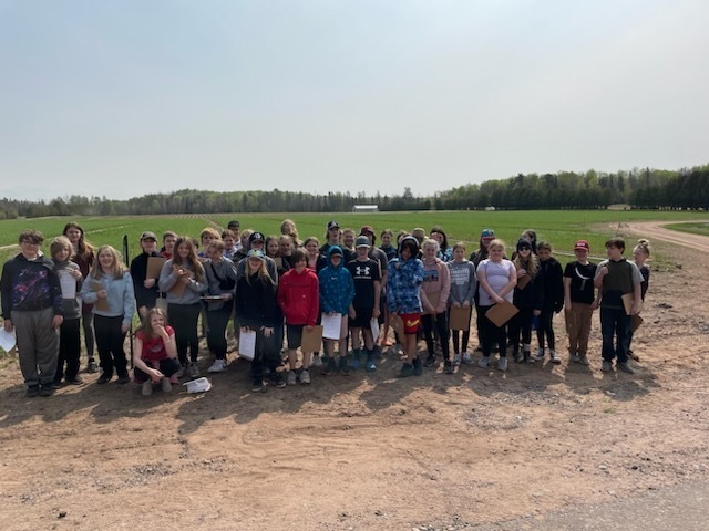 The sixth grade class stands outside at the nursery